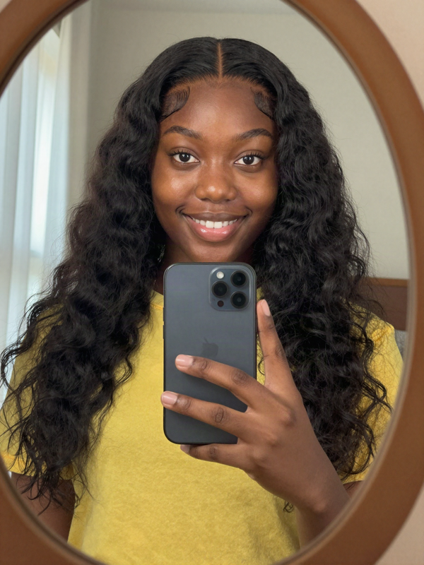 Mirror selfie wearing a black loose wave wig with a middle part